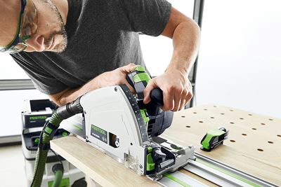 Homem com serra circular da Festool corta uma tábua numa bancada multifuncional