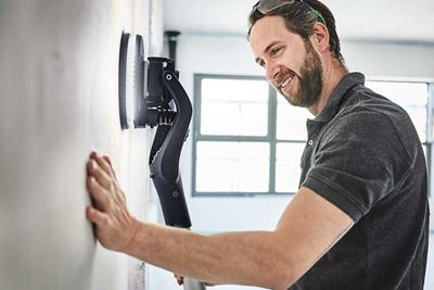 Homem utiliza a Planex com luz para lixa uma parede