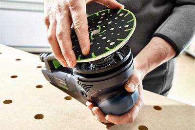 Um artesão coloca os pratos de lixar numa lixadora Festool
