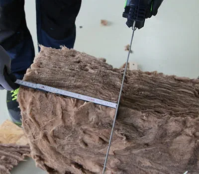 Encostar a fita métrica com a medida e cortar painel de isolamento térmico entre caibros